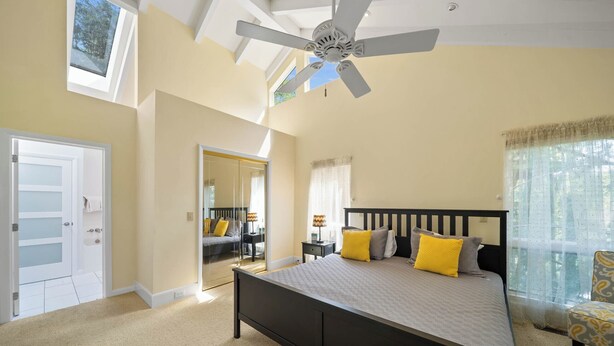 A bedroom with a bed, a ceiling fan, a window, and a door. - Banner Elk Valley Overlook (Banner Elk)