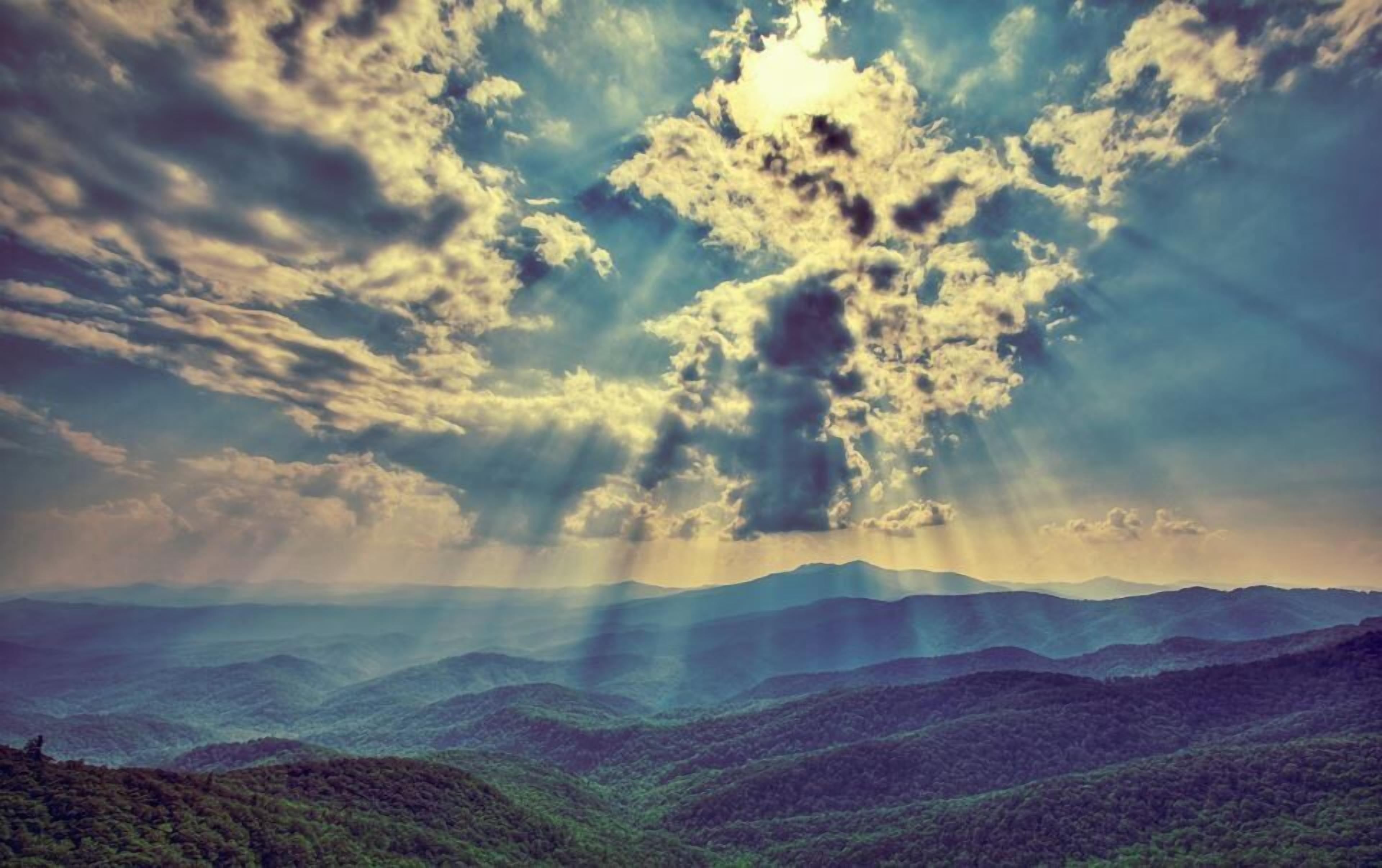 A mountainous landscape with a view of the sky and clouds.