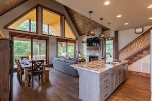 Una cocina amplia con una isla grande, vigas de madera y chimenea de piedra.