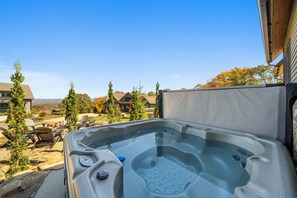 A hot tub with a clear view of the surrounding area, including trees and a distant building. - Soaring Hawk Lodge at Eagles Nest (Elk Park)