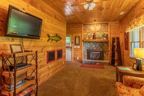 A log cabin interior with a television, fireplace, wooden walls, and a ceiling fan. - A Positive Outlook - 0 Mins to Asu, Hot Tub - Pool Table - Corner Jacuzzi (Vilas)