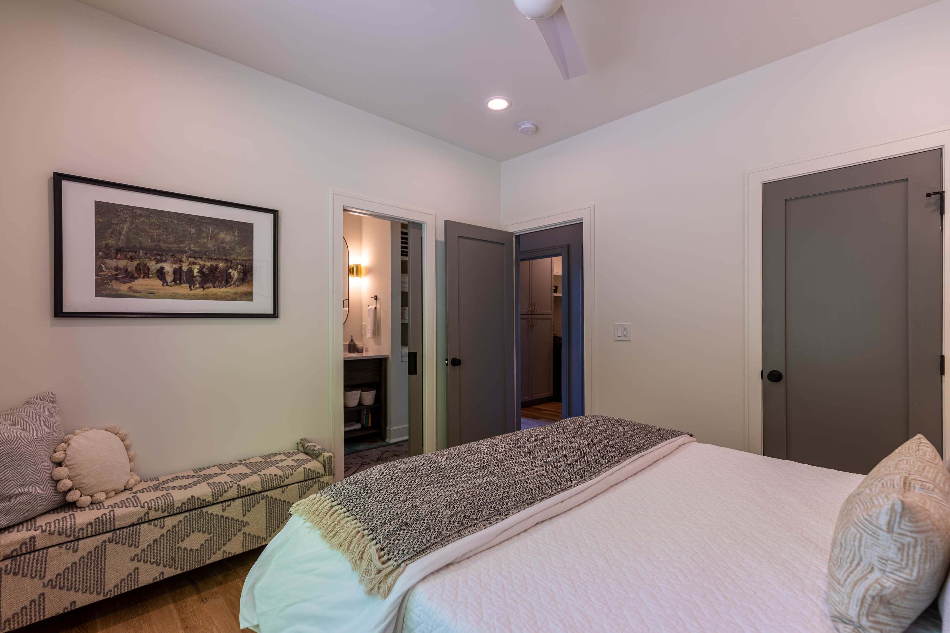 A bedroom with a bed, a sofa, a framed picture, and a wardrobe.