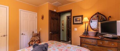 A bedroom with a bed, dresser, television, and teddy bears.