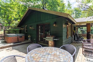 Una cabaña de madera con un patio, barbacoa al aire libre y jacuzzi.