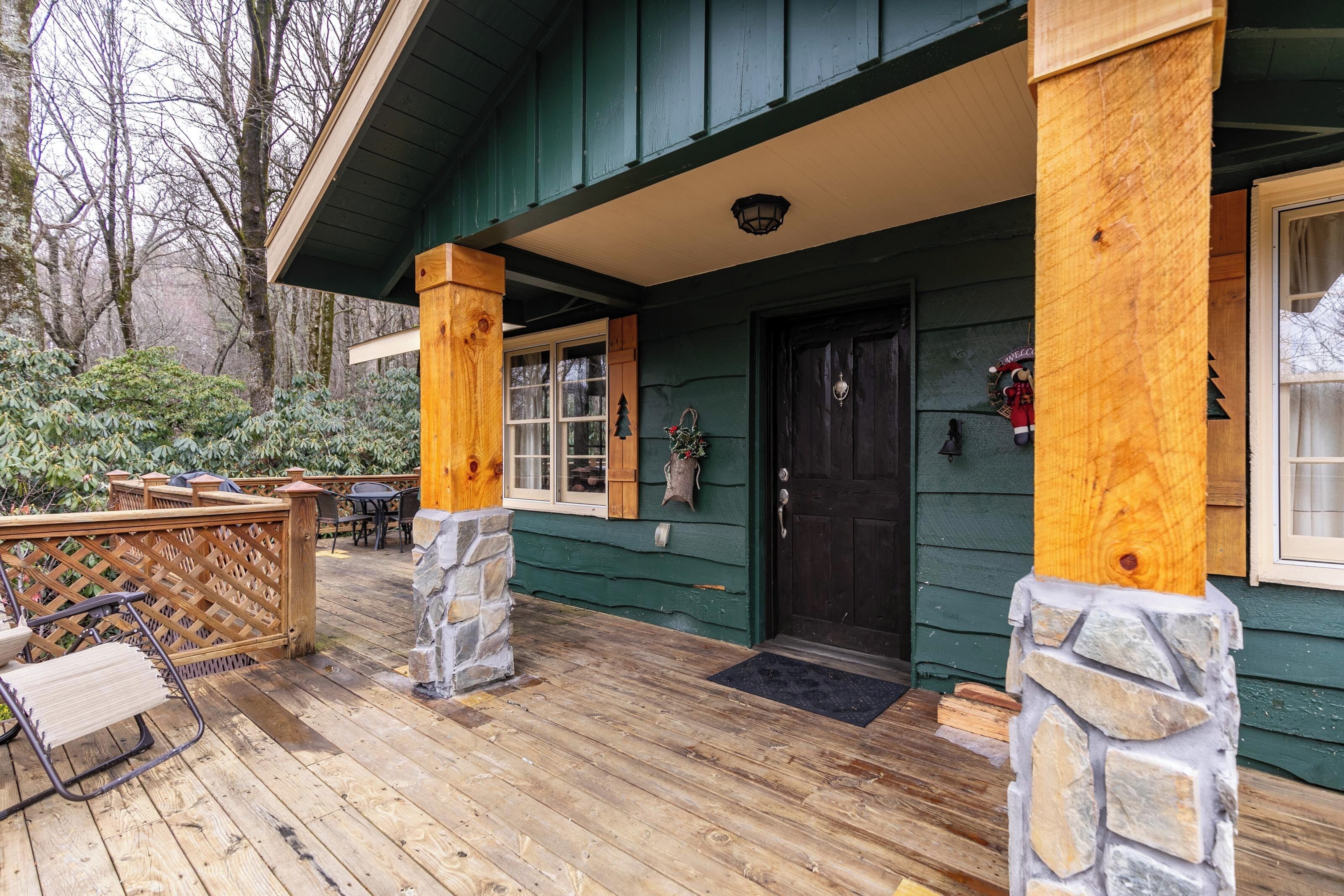 A wooden deck with outdoor furniture, a stone pillar, and a dark-colored door.