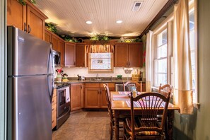 Una cocina con armarios de madera, un refrigerador de acero inoxidable, un microondas y una mesa de comedor con sillas.