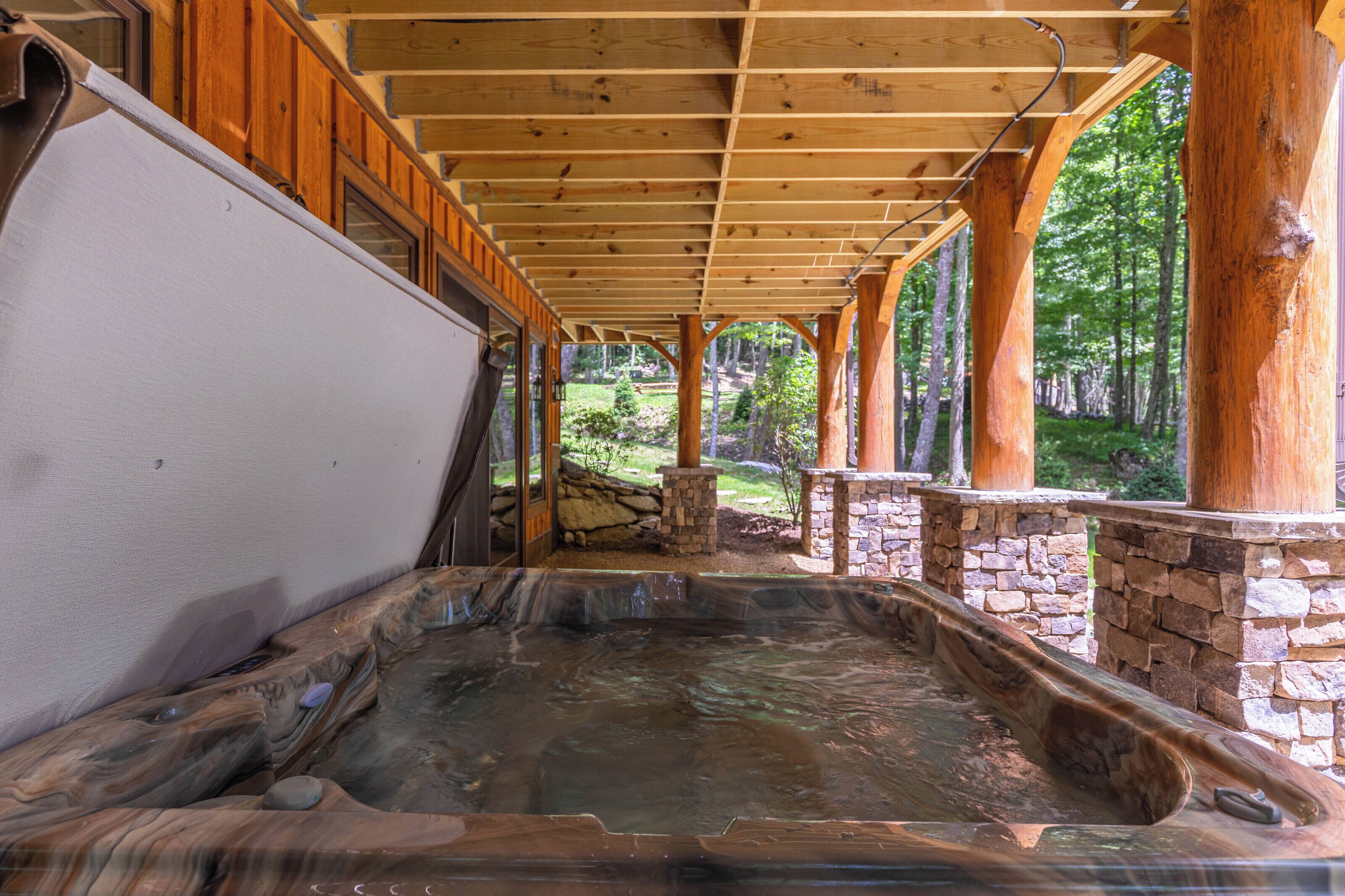 Un espace avec un bain à remous, doté d’un mur en pierre et de poutres en bois.