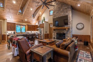 A spacious living area with a stone fireplace, leather seating, and a large TV. - Bear Creek Cabin at Eagles Nest (Banner Elk)