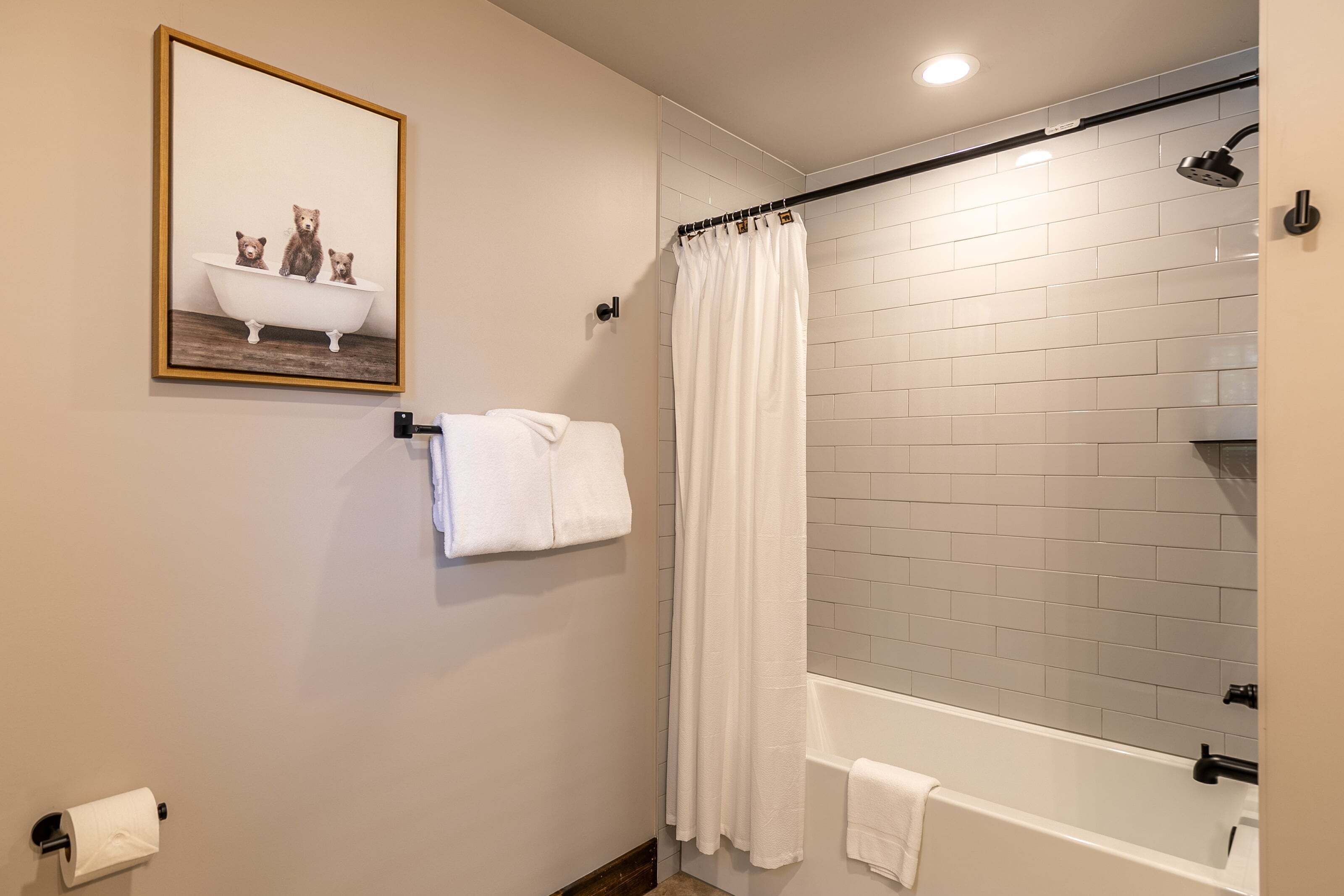 Un bagno con una vasca, una tenda da doccia, un portascopevoli e un porta carta igienica.