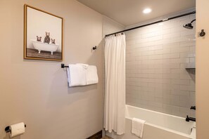 A bathroom with a bathtub, a shower curtain, a towel rack, and a toilet paper holder. - Beagles Rest at Eagles Nest (Banner Elk)