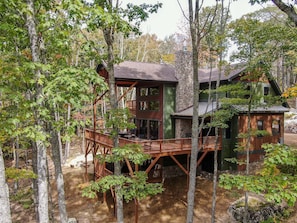 A cabin with a wooden deck, surrounded by trees. - Beagles Rest at Eagles Nest (Banner Elk)