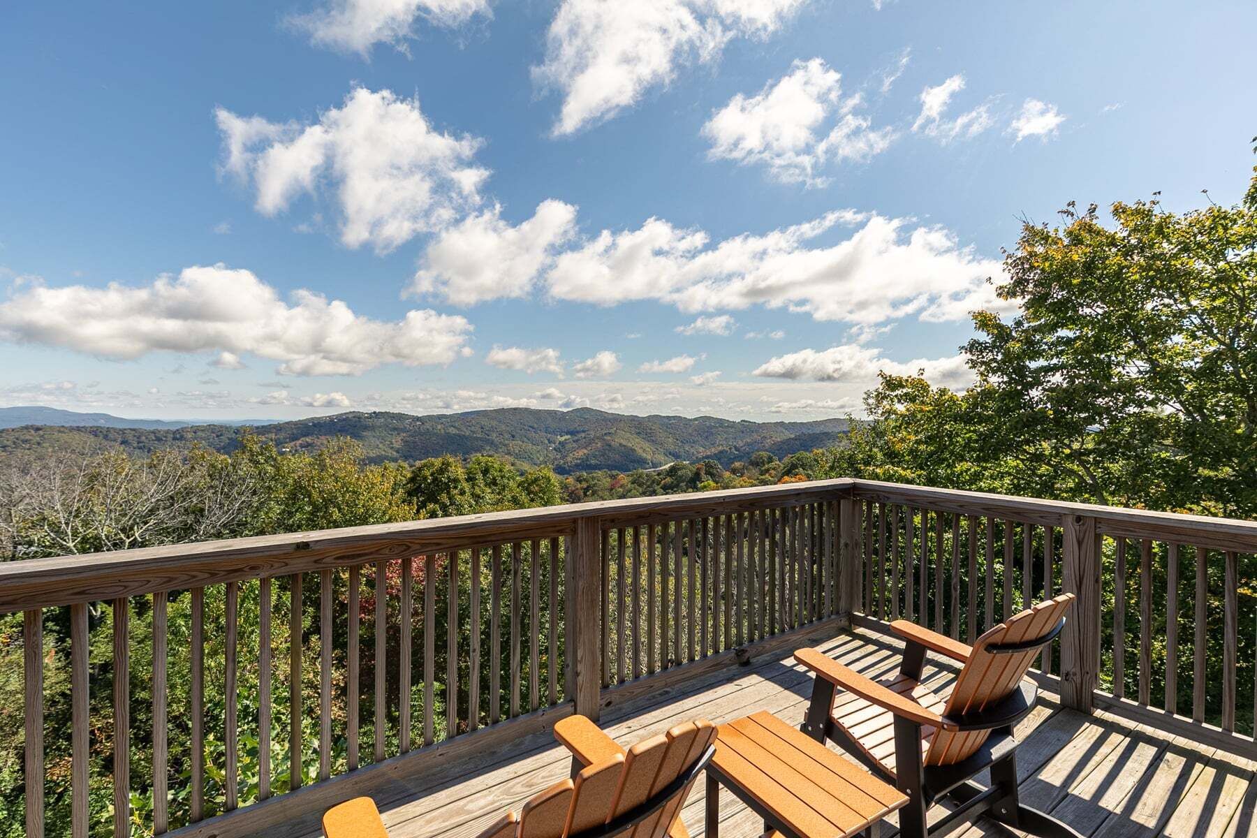 A wooden deck with a view of mountains and a clear sky.