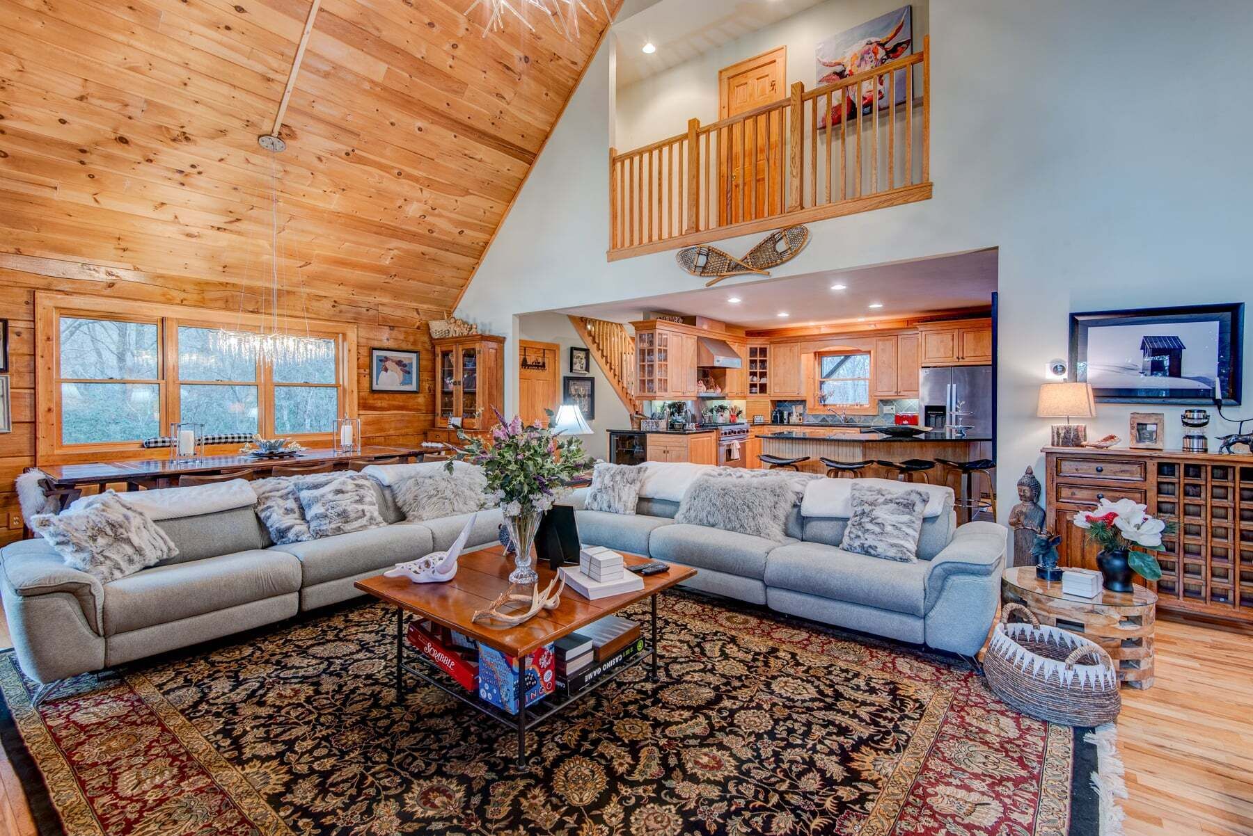 A spacious living area with a large sectional sofa, a coffee table with books, and a patterned rug.