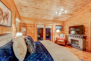 Ein Holzblockhaus-Innenraum mit Bett, Kamin und Deckenleuchte.