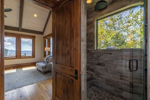 A spacious room with a large window, a wooden door, and a stone shower area. - Heavenly Daze at Eagles Nest (Banner Elk)