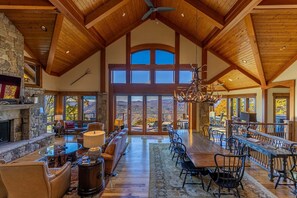 A spacious interior with a high ceiling, stone fireplace, large windows, and a dining area. - Heavenly Daze at Eagles Nest (Banner Elk)