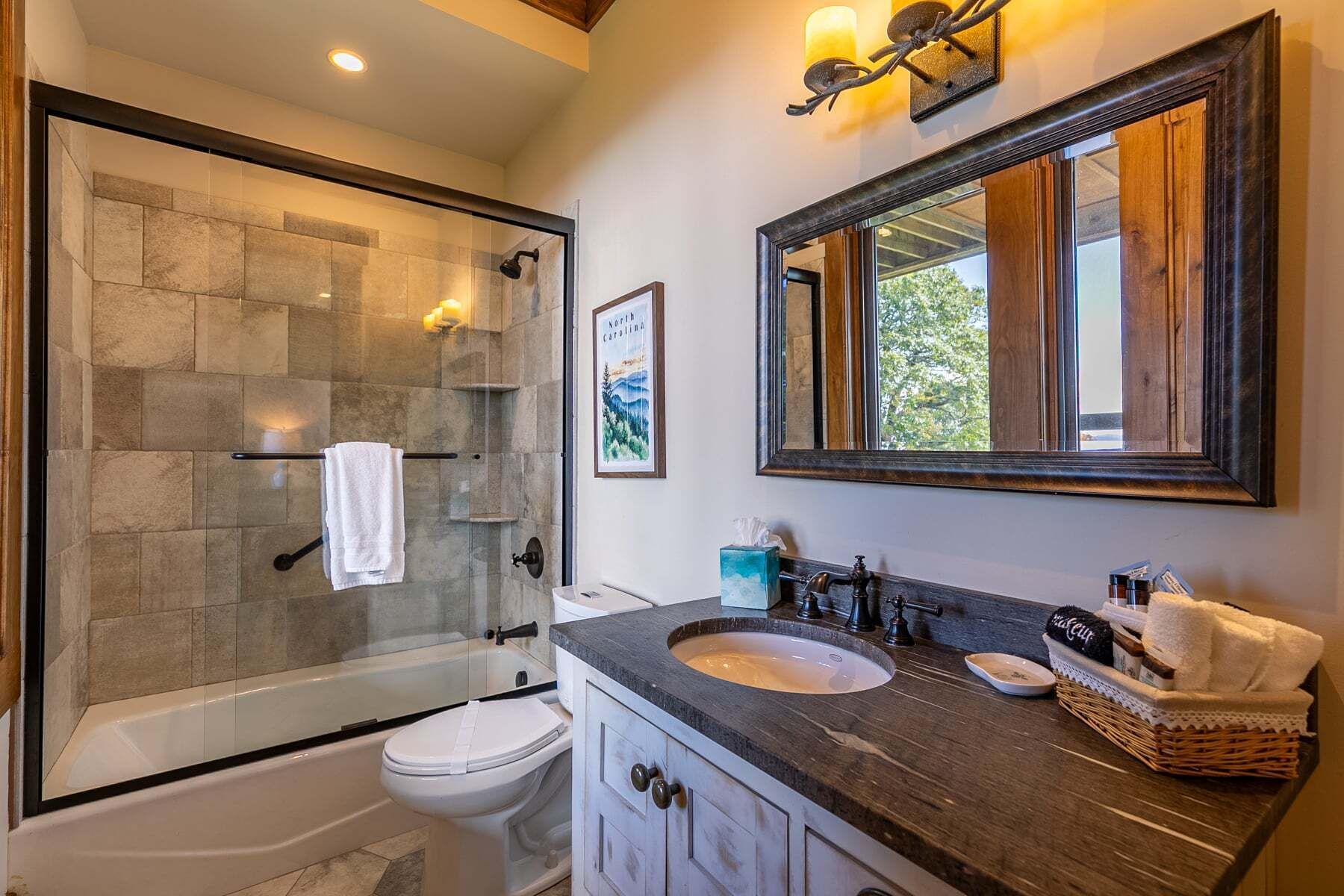 Een moderne badkamer met een douchecabine van glas, een wit toilet, een wastafelmeubel met een wastafel en een grote spiegel.