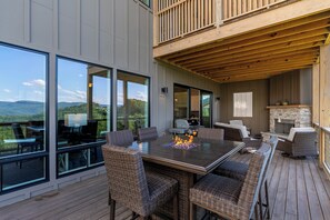A spacious outdoor deck with a large dining table and wicker chairs, overlooking a scenic landscape. - Blue Ridge Sanctuary at Blue Ridge Mountain Club (Lenoir)