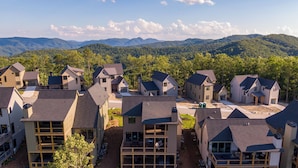 A residential area with modern houses, a central driveway, and a backdrop of mountains. - Blue Ridge Sanctuary at Blue Ridge Mountain Club (Lenoir)