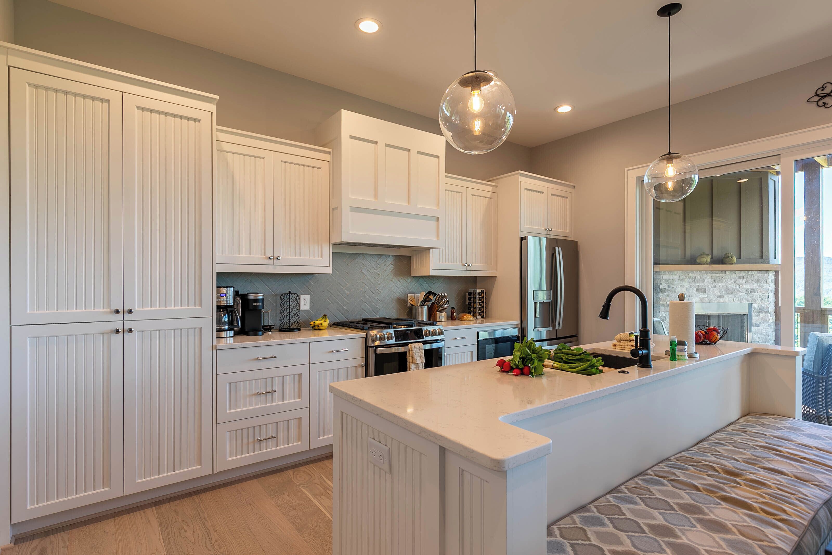 A modern kitchen with white cabinetry, a central island, and pendant lighting.