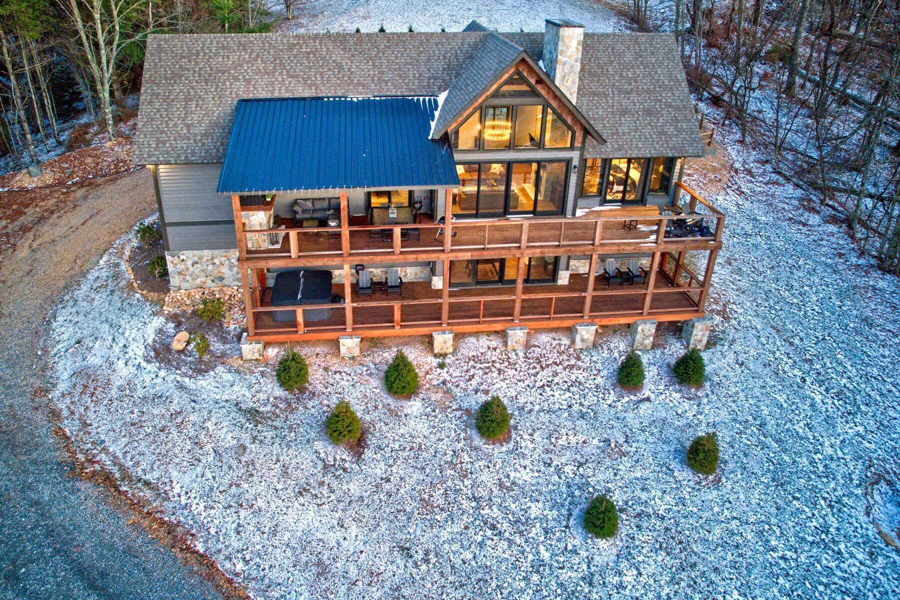 Un grand chalet à plusieurs étages, doté d’un balcon imposant, et entouré d’un paysage enneigé.