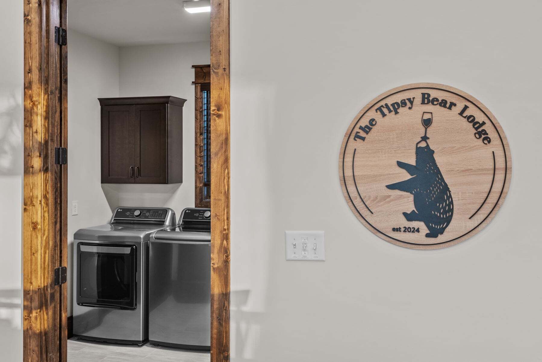 A laundry area with a washing machine, dryer, and wooden cabinet.