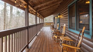 A wooden deck with chairs and tables, a wooden ceiling, and windows with curtains. - Weathering Heights (Boone)