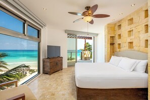 Ein Schlafzimmer mit Bett, Deckenventilator, Fernseher und Blick auf den Strand.