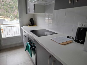 Une cuisine équipée d’une cuisinière intégrée, d’une machine à café et d’une fenêtre donnant sur les arbres.