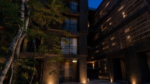 Een modern gebouw met meerdere verdiepingen, grote ramen en een binnentuin met bomen en een pad.