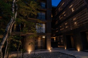 A modern building with multiple floors, large windows, and a courtyard with trees and a pathway. - Romantic Jungle Studio, Rooftop Pool & Lounge Fast WIFI/AC in Tulum (Tulum)