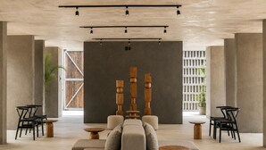 Een modern interieur met een bank, twee houten tafels en zwarte stoelen.
