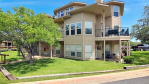 A two-story building with a balcony, a fire lane, and a grassy area. - 3 Bedroom Lake Escape steps to resort & marina (Pottsboro)