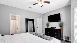 A bedroom with a bed, a ceiling fan, a dresser, a TV, and a door. - 3 Bedroom Lake Escape steps to resort & marina (Pottsboro)