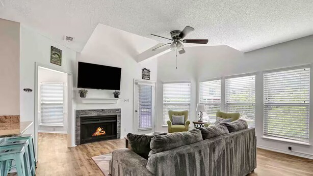 A living room with a fireplace, a sofa, a television, and a ceiling fan. - 3 Bedroom Lake Escape steps to resort & marina (Pottsboro)