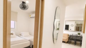Una habitación de hotel con cama, mesita de noche y un ventilador de pared.