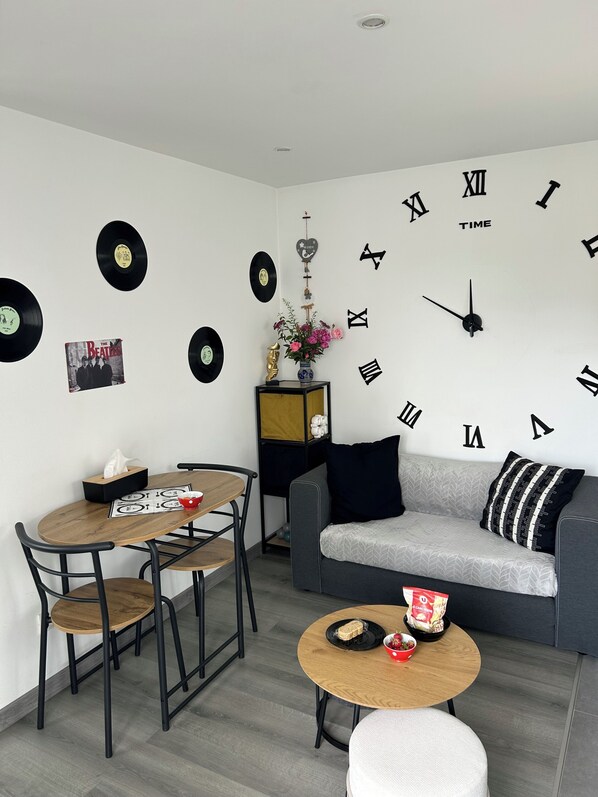 A modern living room with a round dining table, a sofa, and a wall clock.