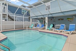 An indoor swimming pool with a covered area, blue lounge chairs, and a staircase leading to an upper level. - Dolphin Run | Heated Pool, 3-Min Walk to Beach! (Fort Myers Beach)
