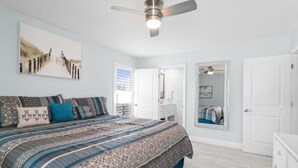 A bedroom with a bed, a ceiling fan, a large mirror, and a door. - Dolphin Run | Heated Pool, 3-Min Walk to Beach! (Fort Myers Beach)