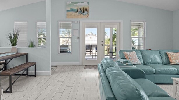 A spacious living area with a teal sofa, a wooden bench, and a ceiling fan. - Dolphin Run | Heated Pool, 3-Min Walk to Beach! (Fort Myers Beach)