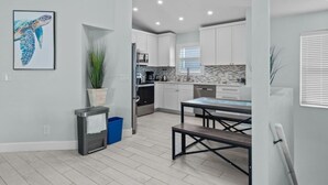 A modern kitchen with white cabinets, a dining table, and a potted plant. - Dolphin Run | Heated Pool, 3-Min Walk to Beach! (Fort Myers Beach)