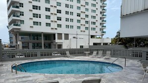 En tagterrasse med swimmingpool, liggestole og en moderne bygning i baggrunden.