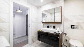 Un bagno moderno con lavandino, specchio e water bianchi.