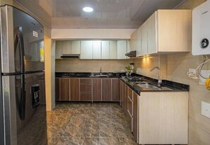 Una cucina dotata di frigorifero, fornelli, lavello e scaldabagno.