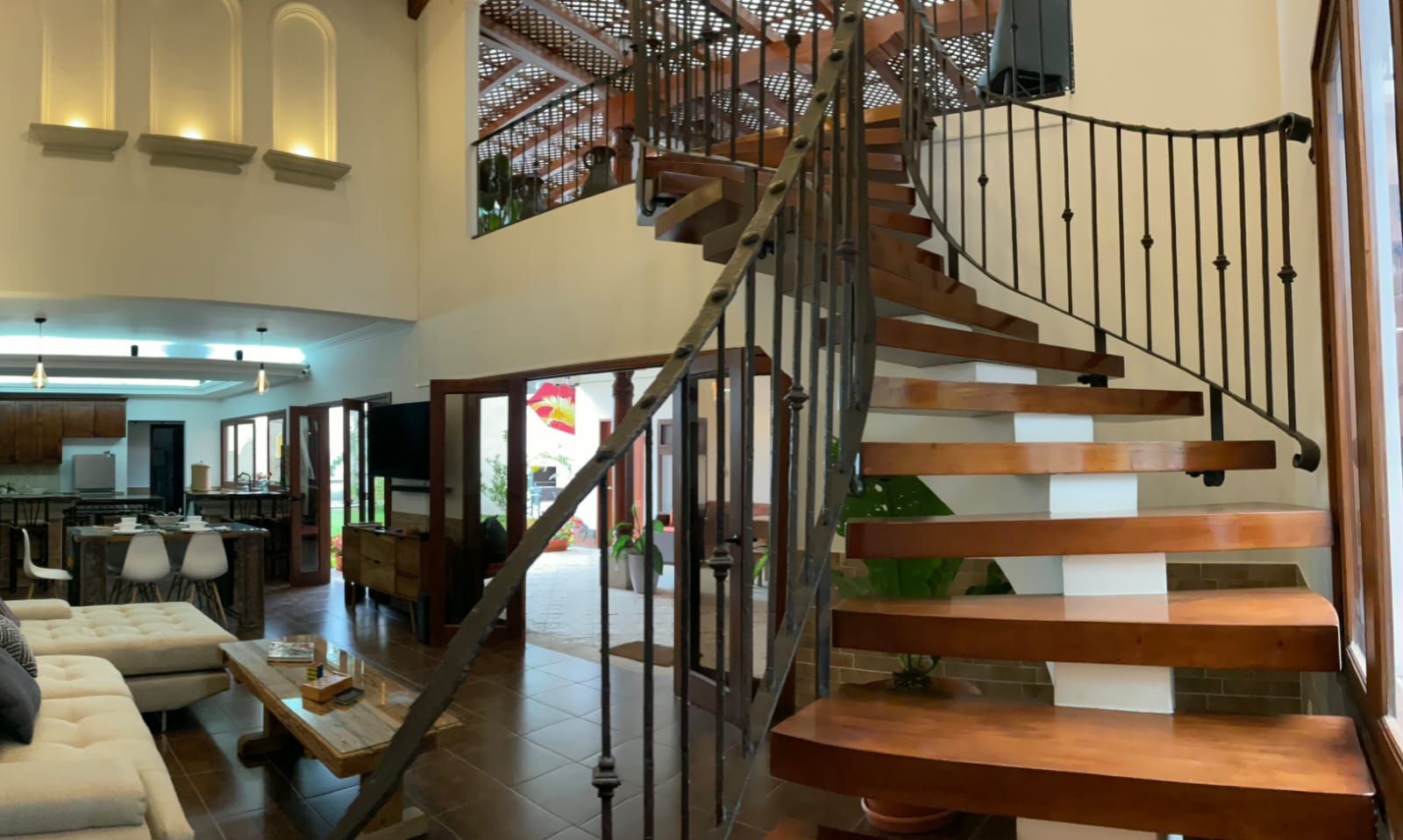 A spacious living area with a modern staircase, a dining area, and a kitchen.