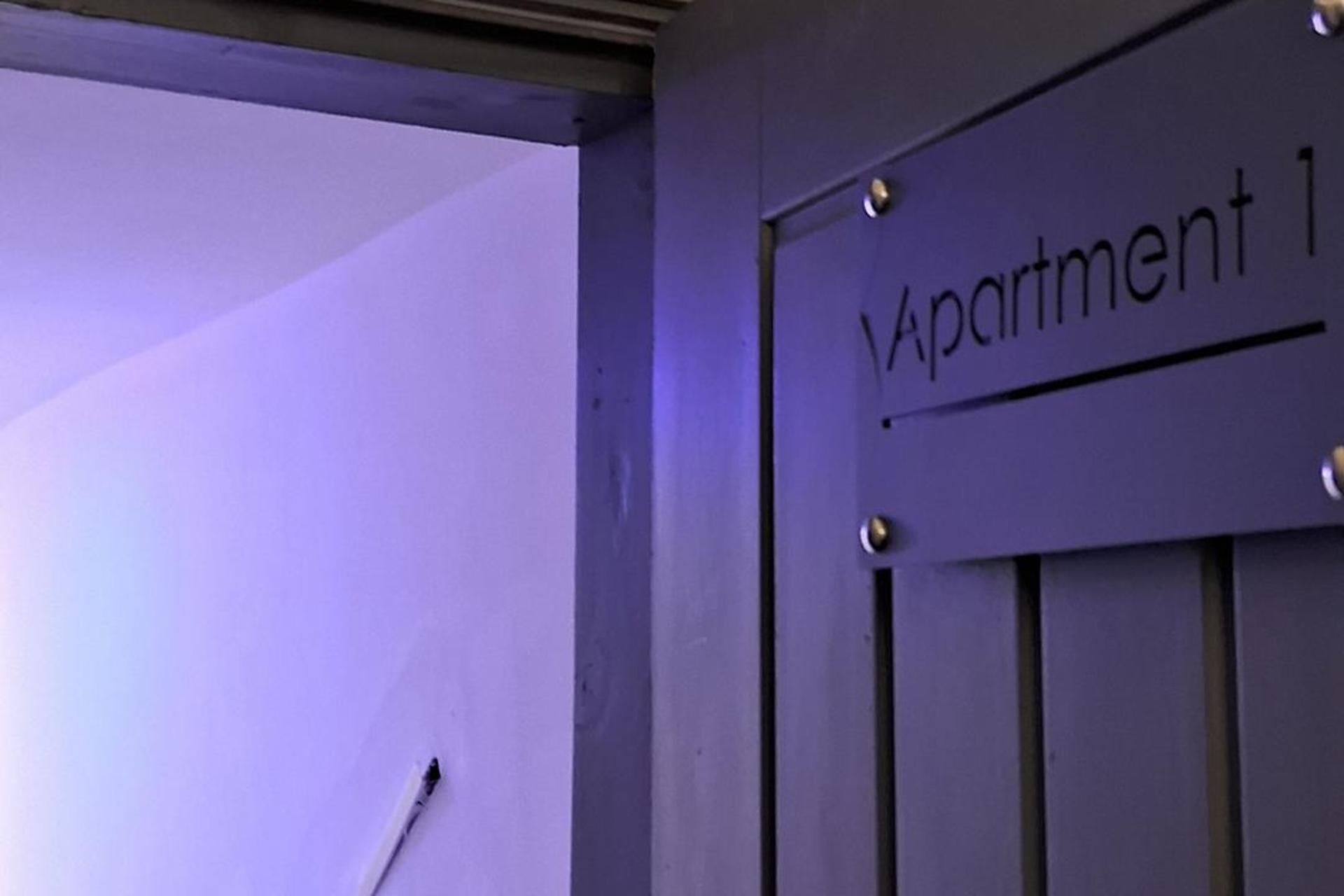 Una porta amb la inscripció 'Apartment 1', un mànec metàl·lic i una presa elèctrica visible.