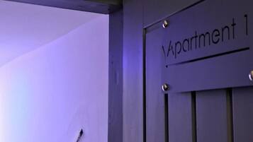 Una porta amb la inscripció 'Apartment 1', un mànec metàl·lic i una presa elèctrica visible.