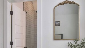 A bedroom with a bed, a wooden dresser, a mirror, and a door leading to a bathroom. - SoCo 2BR South Austin Modern Gem & Very Walkable! (Austin)