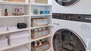 A laundry room with stacked towels, wicker baskets, and a washing machine. - SoCo 2BR South Austin Modern Gem & Very Walkable! (Austin)