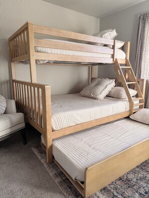 A bunk bed with a ladder, a chair, and a patterned wall.
